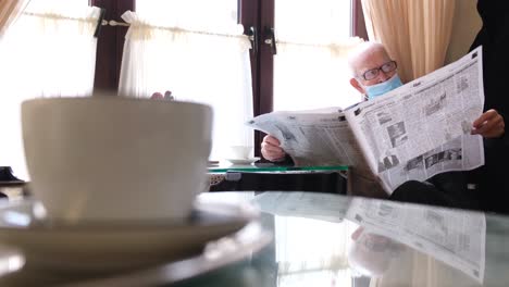 old grandfather reads a newspaper sitting in a cafe old grandfather reads a newspaper sitting in a cafe senor drinks tea and reads the fresh press