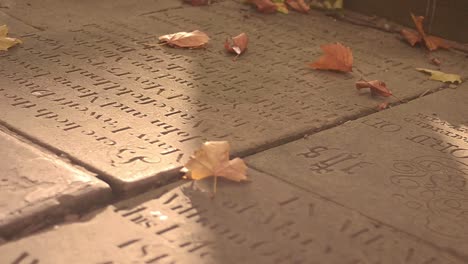 gravestones in churchyard path as autumn leaves blow by