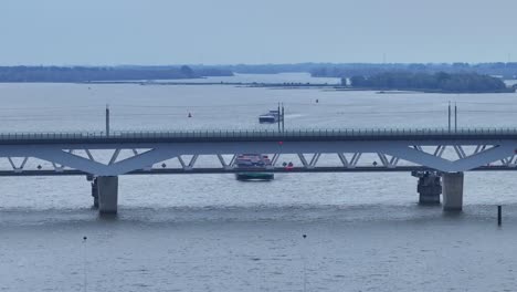 the moerdijk bridges in netherlands with cars moving and a ferry in passing underneath