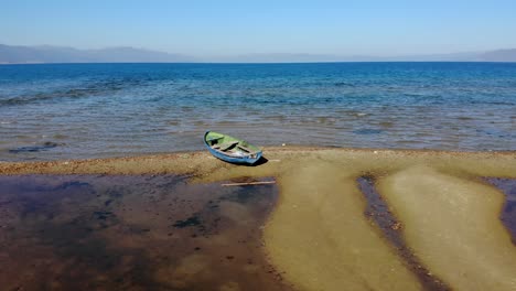 Barco-De-Pesca-Abandonado-En-La-Orilla-Arenosa-Del-Lago-De-Montaña-En-Pogradec,-Albania