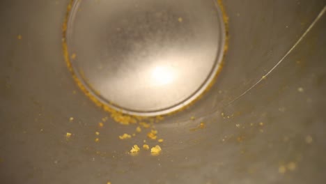 pulling out of the bottom of an empty chip can, many chip crumbs visible at the bottom ring