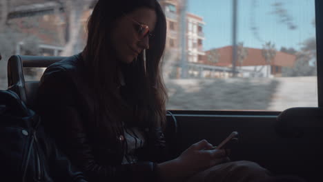 Una-Chica-De-Pelo-Largo-Con-Gafas-De-Sol-Sentada-En-Un-Autobús-En-Movimiento