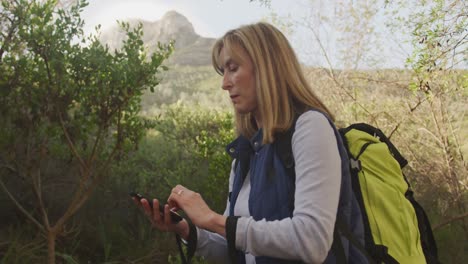 mujer mayor activa usando el teléfono en el bosque