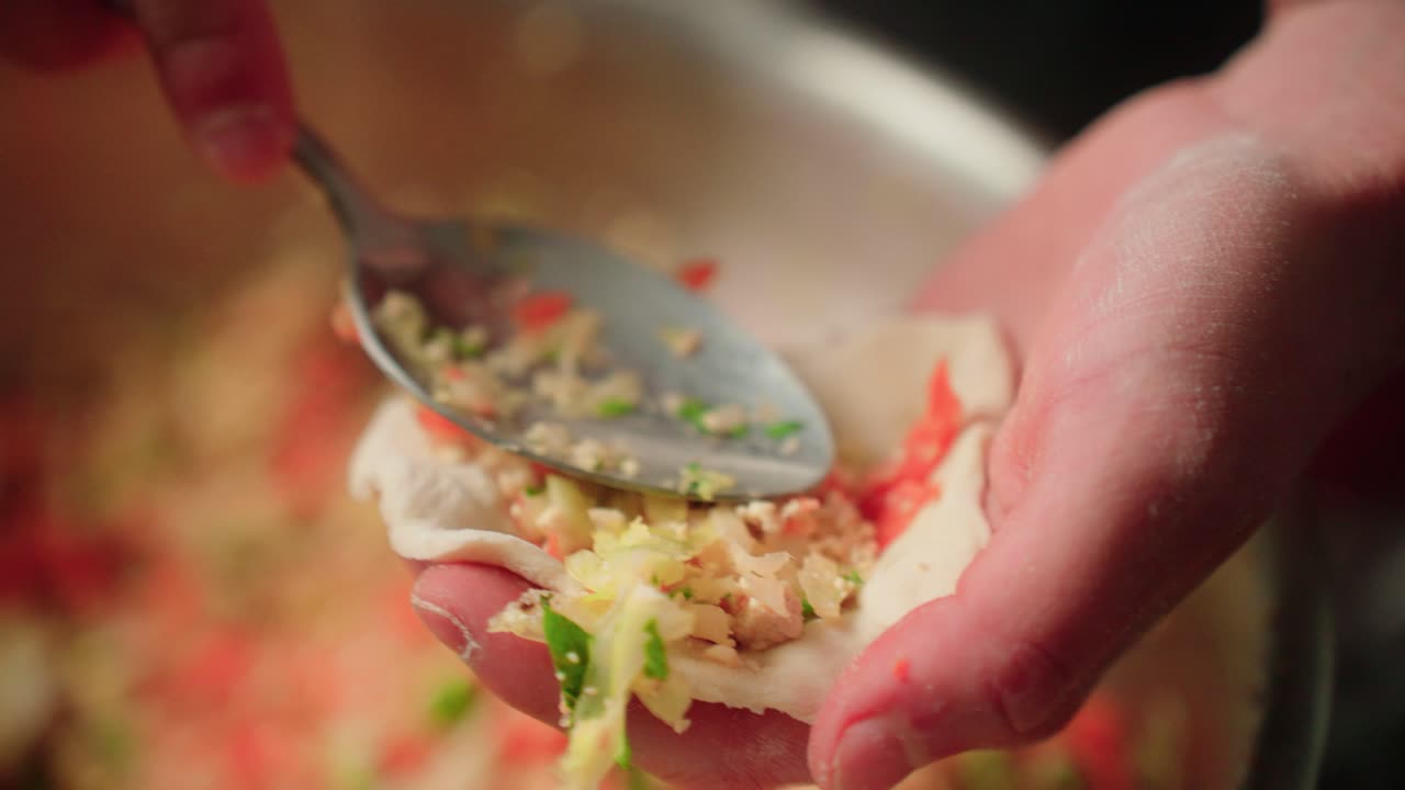 Packing a dumpling with filling and folding it up