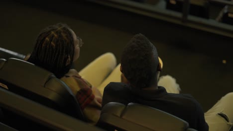 african american young couple came to the movie theatre watching film, taking popcorn from bucket, top view