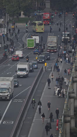 traffic and people crossing westminster bridge next to the houses of parliament, london, uk in vertical