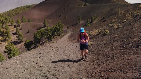 A-shot-of-a-woman-climbing-a-dusty-trail-in-a-volcanic-terrain