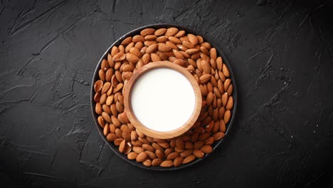 composición de semillas de almendras y leche colocadas sobre fondo de piedra negra