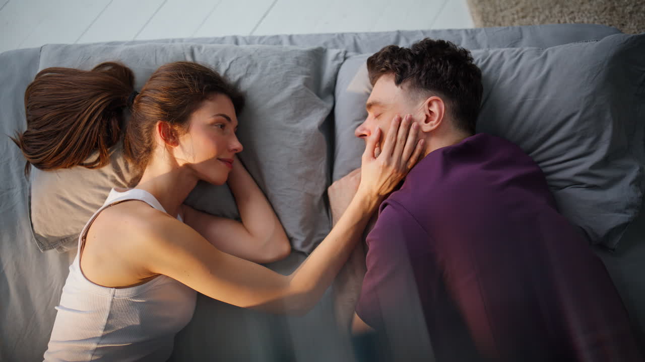Enamoured woman touching man face lying bedroom mattress closeup. Love pair