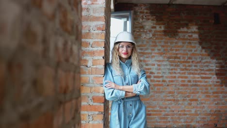 the process of building a dream house. a young woman in a work helmet and denim clothes and goggles stands at the construction site.