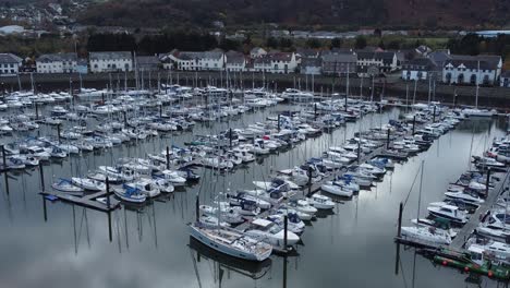 scenic luxurious waterfront harbour apartment village yachts and sailboats under mountain coastline aerial view zoom in