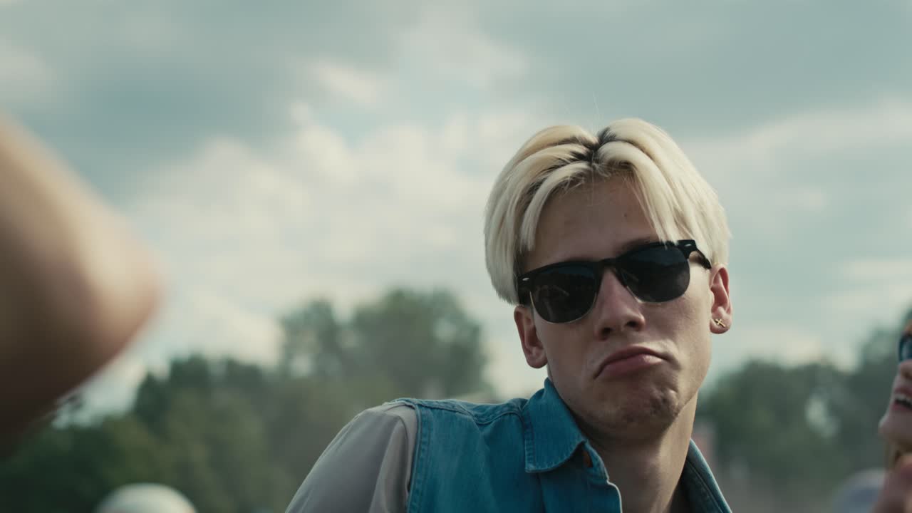 젊은 백인 친구들이 음악 페스티벌에서 손을 들고 춤을 추고 있습니다.