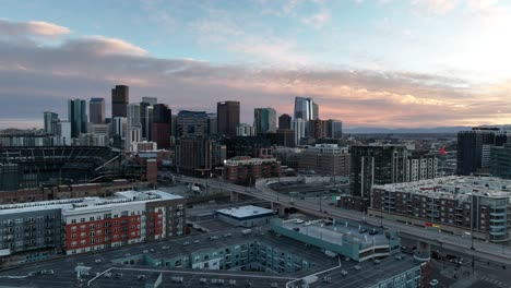 Vista-Panorámica-Aérea-De-La-Ciudad-De-Denver-Colorado-Al-Atardecer,-Barrio-Residencial-Y-Estadio-Junto-Al-Distrito-Del-Centro