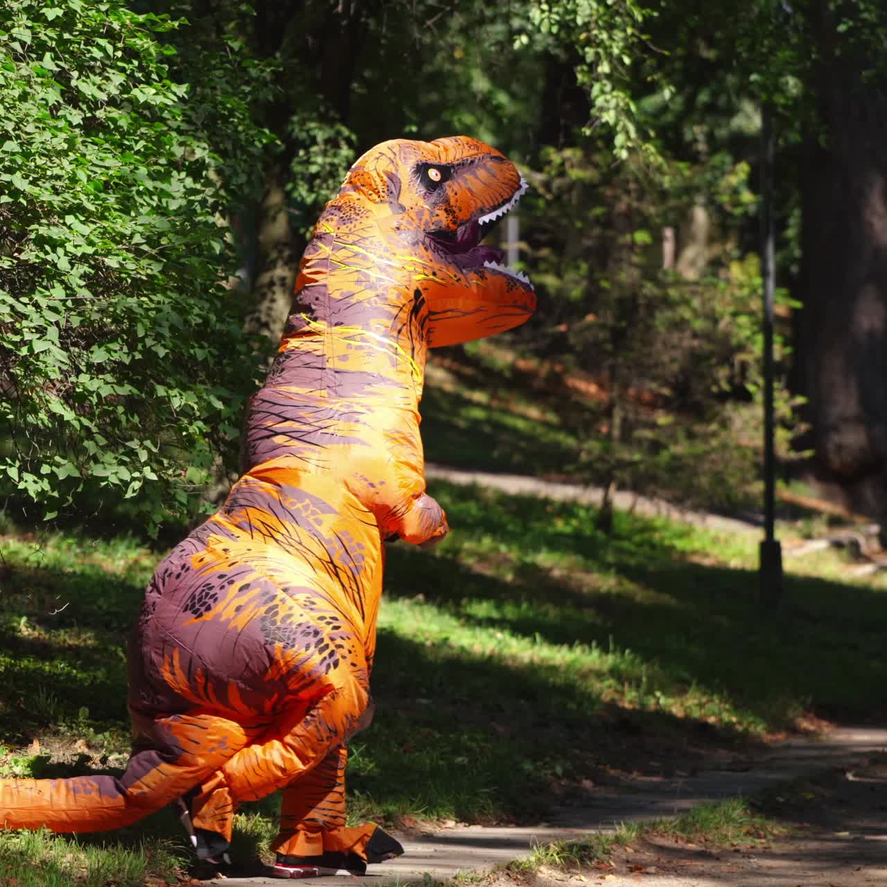 Joyful person in dragon costume. Funny person in dragon carnival suit having fun in the park in summertime.