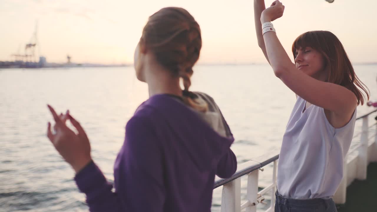 해가 지면 배의 갑판에서 춤을 추는 두 여자친구