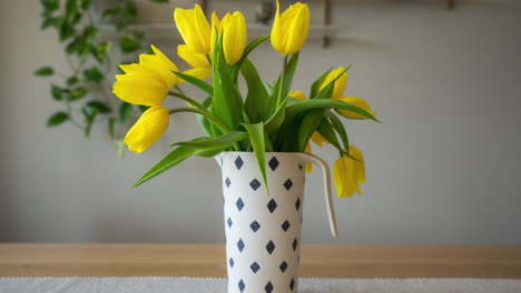 drooping yellow tulips in flower vase rising