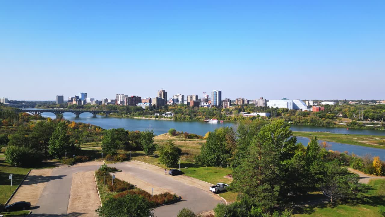 Sideways drone move shows Saskatoon landmarks, river crossing, clear fall sky