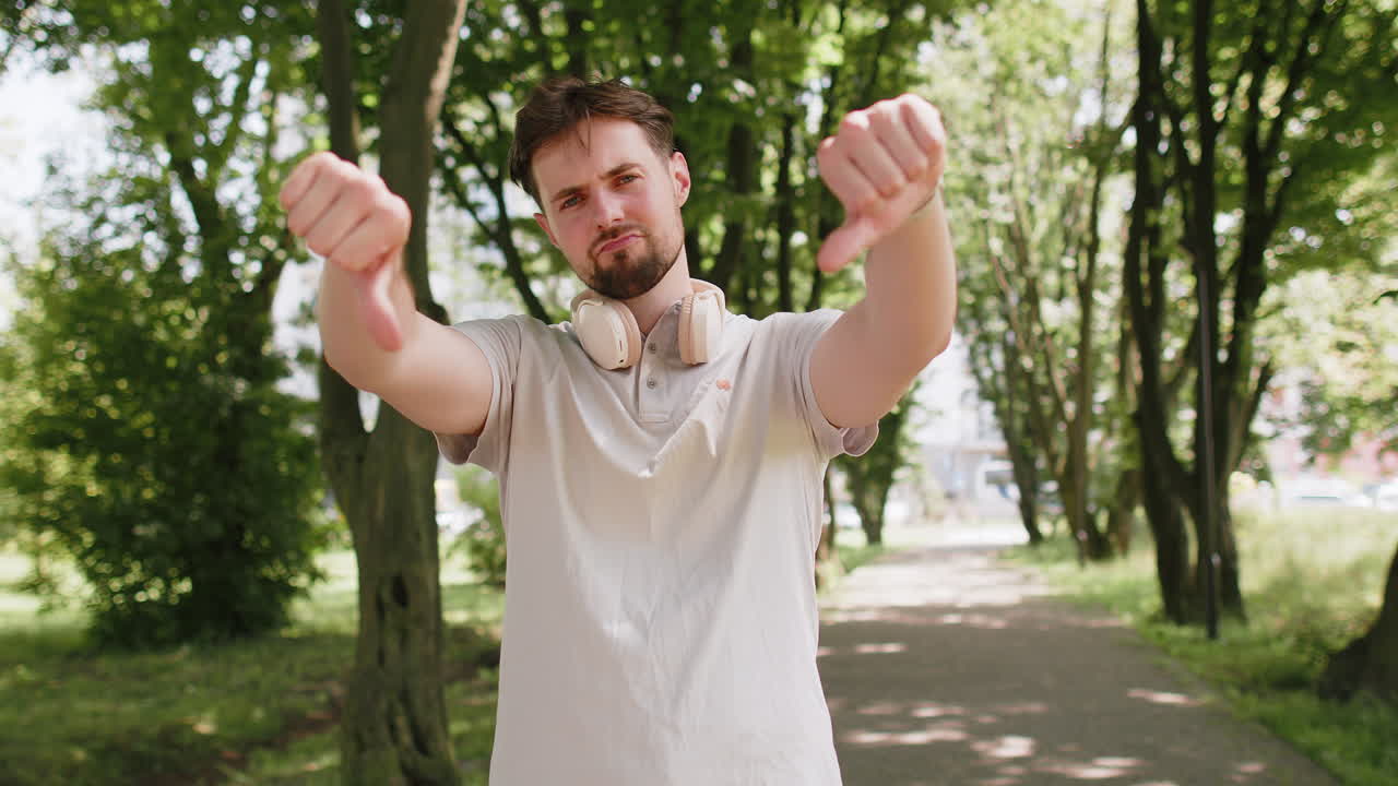 Sad upset dissatisfied loser man jogger showing thumb down bad result unmotivated disagree dislike