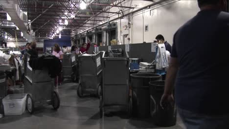 pan across workers in a newspaper factory sorting and stacking papers