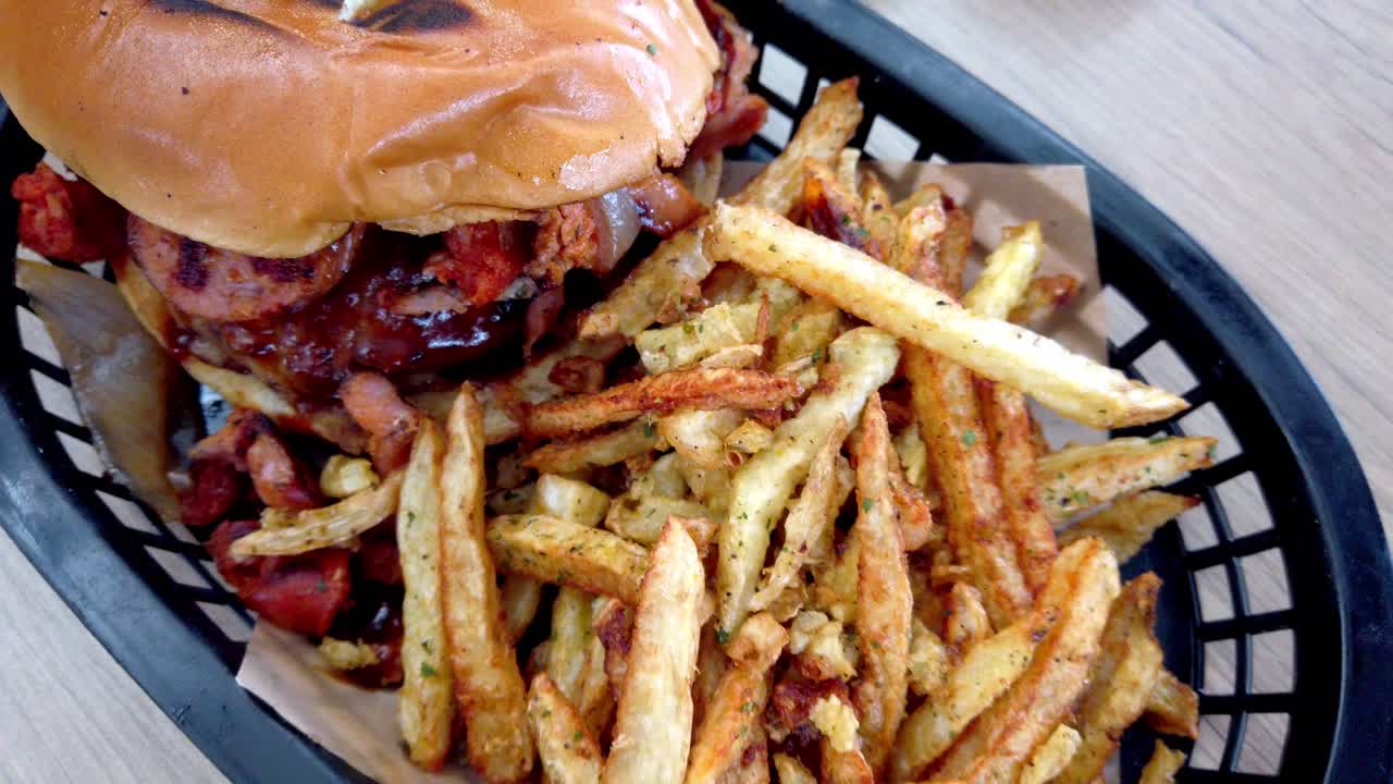Close up of a grilled burger bun with fries in a basket served on a wooden table