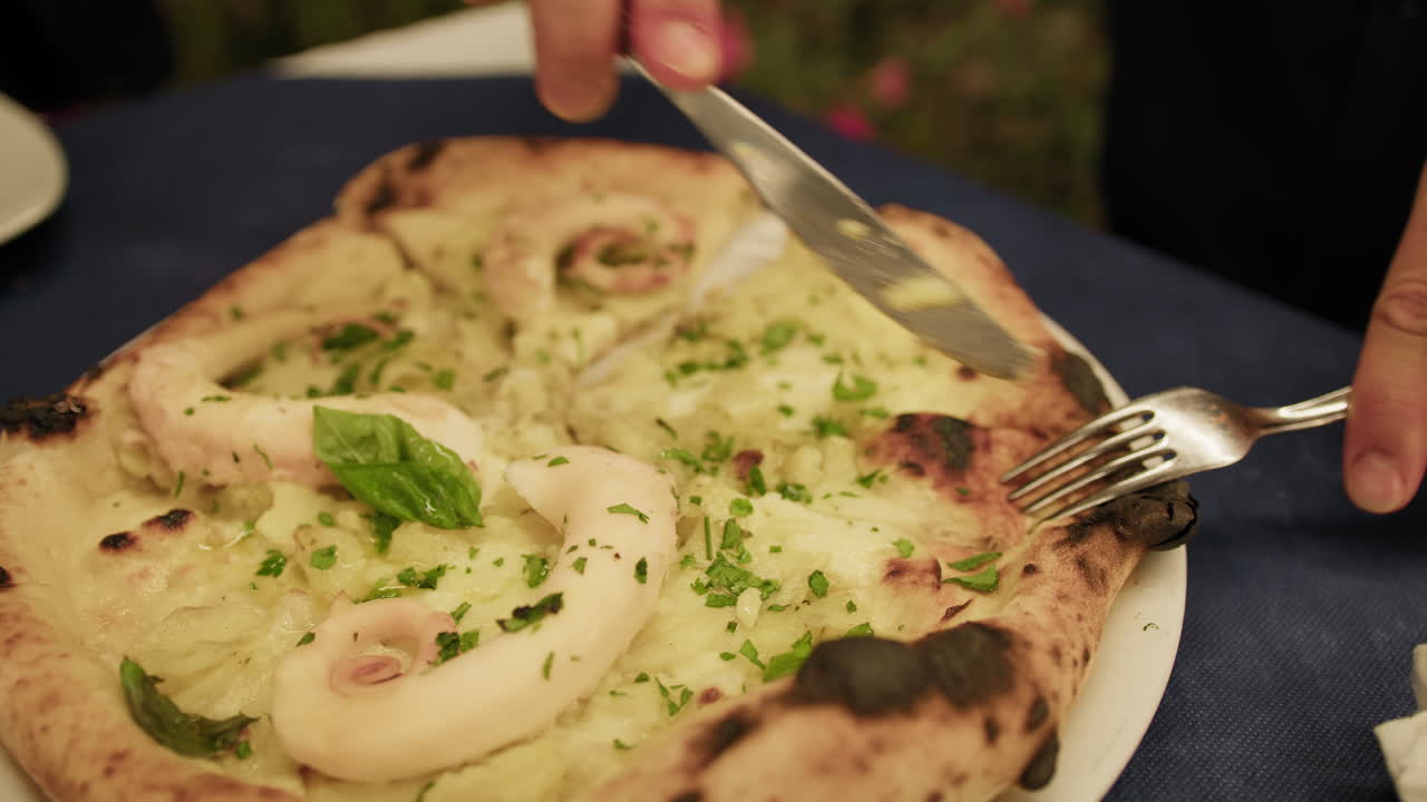 Hands Of A Man Cutting The Gourmet Fish Pizza With Fork And Knife