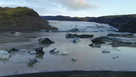 aerial drone cinematic to the right movement of solheimajokull glacier iceland lagoon and icebergs late afternoon