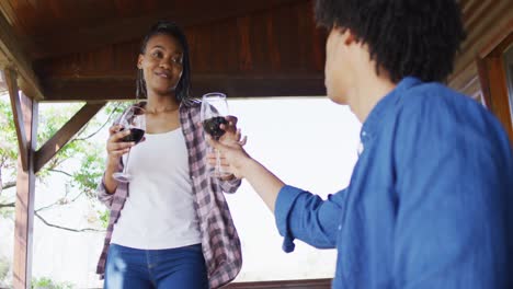 Feliz-Pareja-Afroamericana-Bebiendo-Vino-En-Una-Cabaña-De-Madera,-Cámara-Lenta