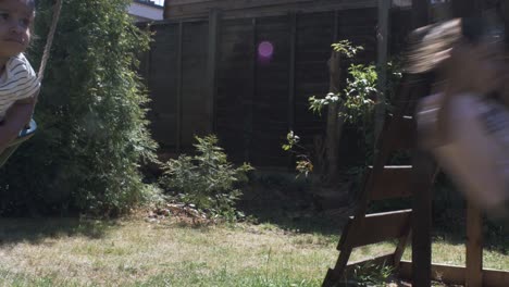 Cute-Baby-And-Older-Sister-On-Swing-Together-In-The-Garden