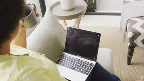video de una mujer afroamericana de tamaño grande sentada en el sofá con una computadora portátil con espacio para copiar