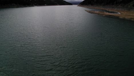 drone aerial view flying over dark moody body of water during a cloudy day with dramatic light near sapphire point dillon reservoir colorado