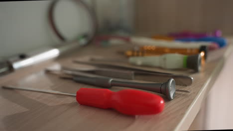 a close-up view of a variety of tools neatly arranged on a wooden workbench, the tools include screwdrivers, tweezers, and other precision instruments