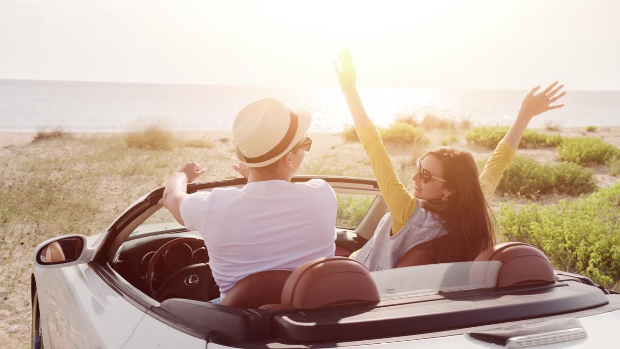una pareja disfrutando de un viaje por carretera en un descapotable junto a la playa
