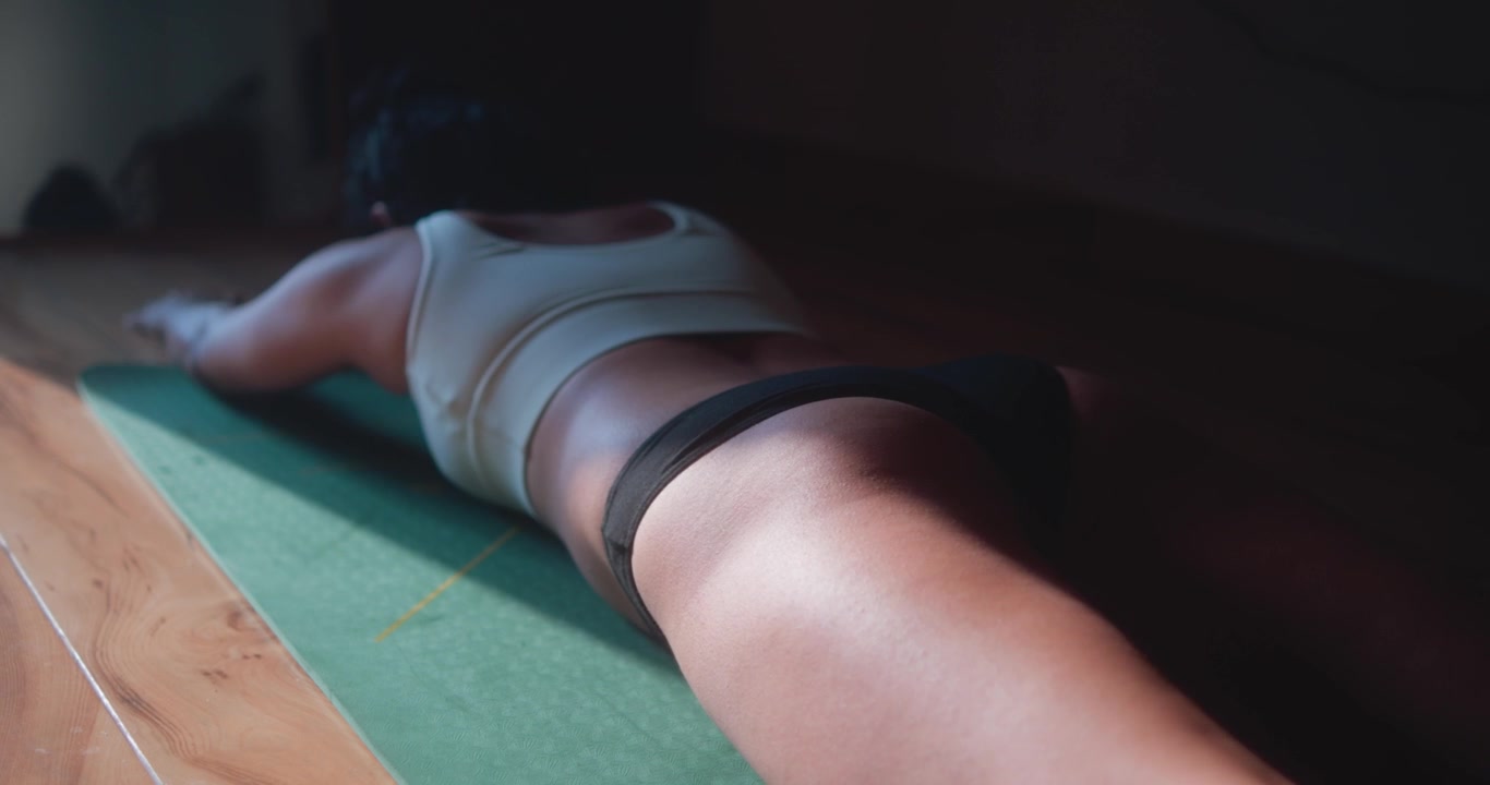 Donna esegue sollevamenti Superman su tappetino da yoga durante un allenamento a casa.