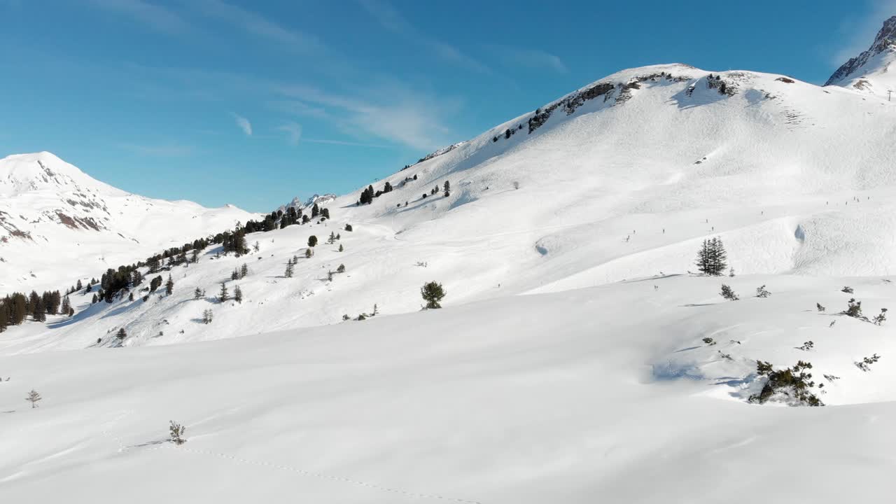 Drone view flying over several skiers enjoying the mountain ranges in Warth, a small municipality in Vorarlberg, Austria on a clear and sunny day in 4K