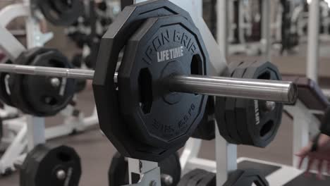 man placing weight plate on bench press in gym