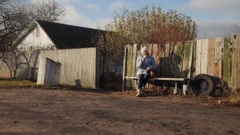 mujer anciana sentada en un banco en un entorno rural