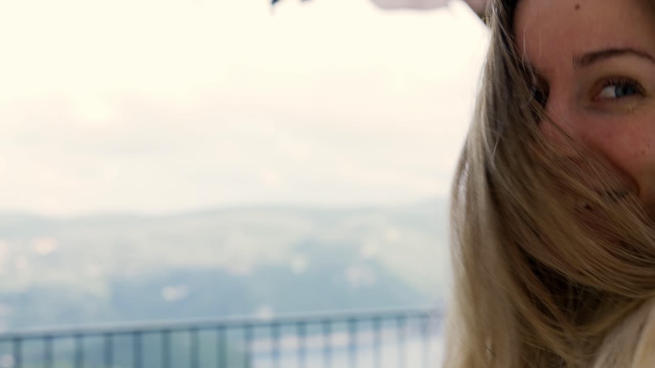 Woman on terrace with gorgeous mountain view follows the camera