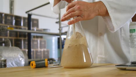 male worker stirring liquor in flask 4k