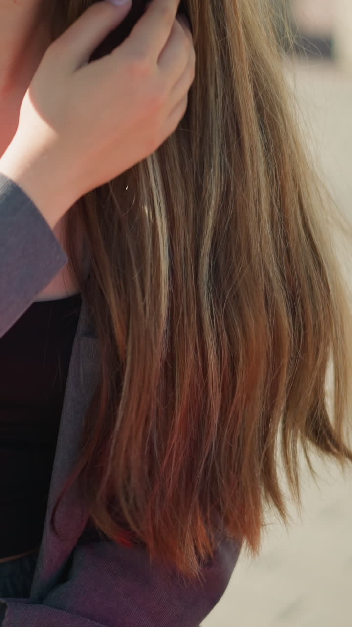 회색 셔츠 에 검은색 크로프 을 입은 여성의 클로즈업, 캐주얼하게 머리카락을 만지고, 빨간색 쇼핑 가방이 에 보이고, 배경이 약간 흐릿합니다.