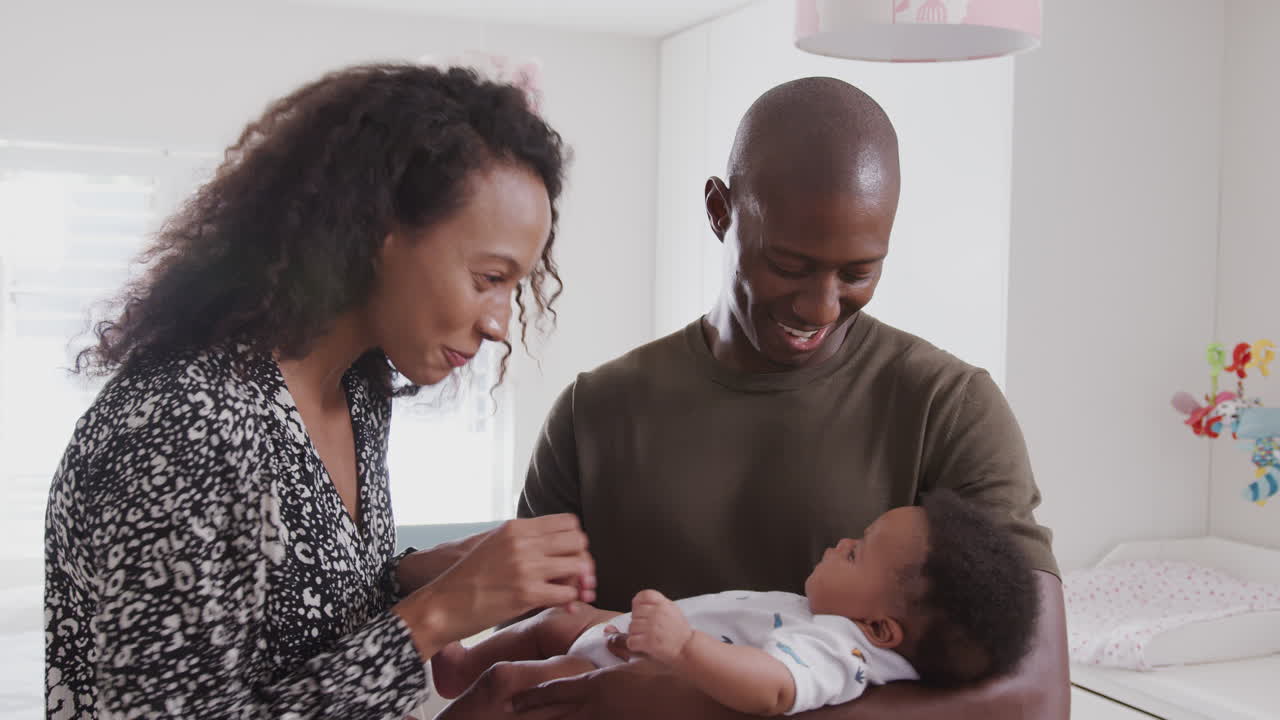 Loving Parents Standing In Nursery At Home Cuddling Baby Son