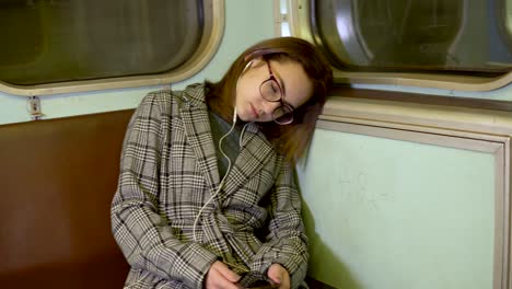 a young woman fell asleep on a subway train. girl with headphones in the ears. old subway car