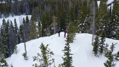 Aerial-orbiting-shot-of-group-of-people-on-a-snowy-mountain