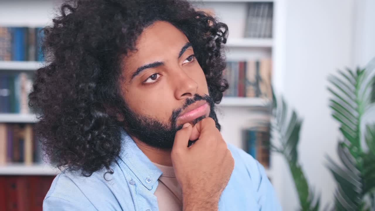 Focused indian man stands in office looks in front of himself and thinking