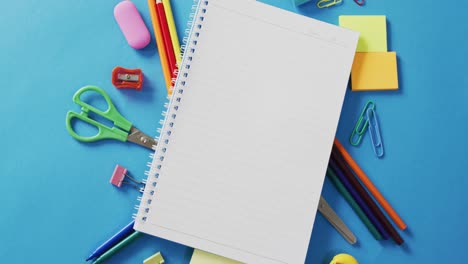 Video-of-notebook-with-copy-space-and-school-equipment-on-blue-background