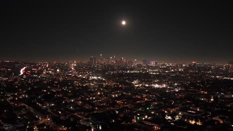 wide tilting-up aerial shot of downtown los angeles under a full moon in southern california. 4k