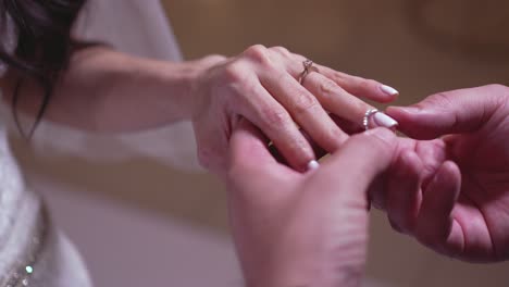 the groom puts the diamond ring on his bride during the day of the wedding ceremony to become new spouses