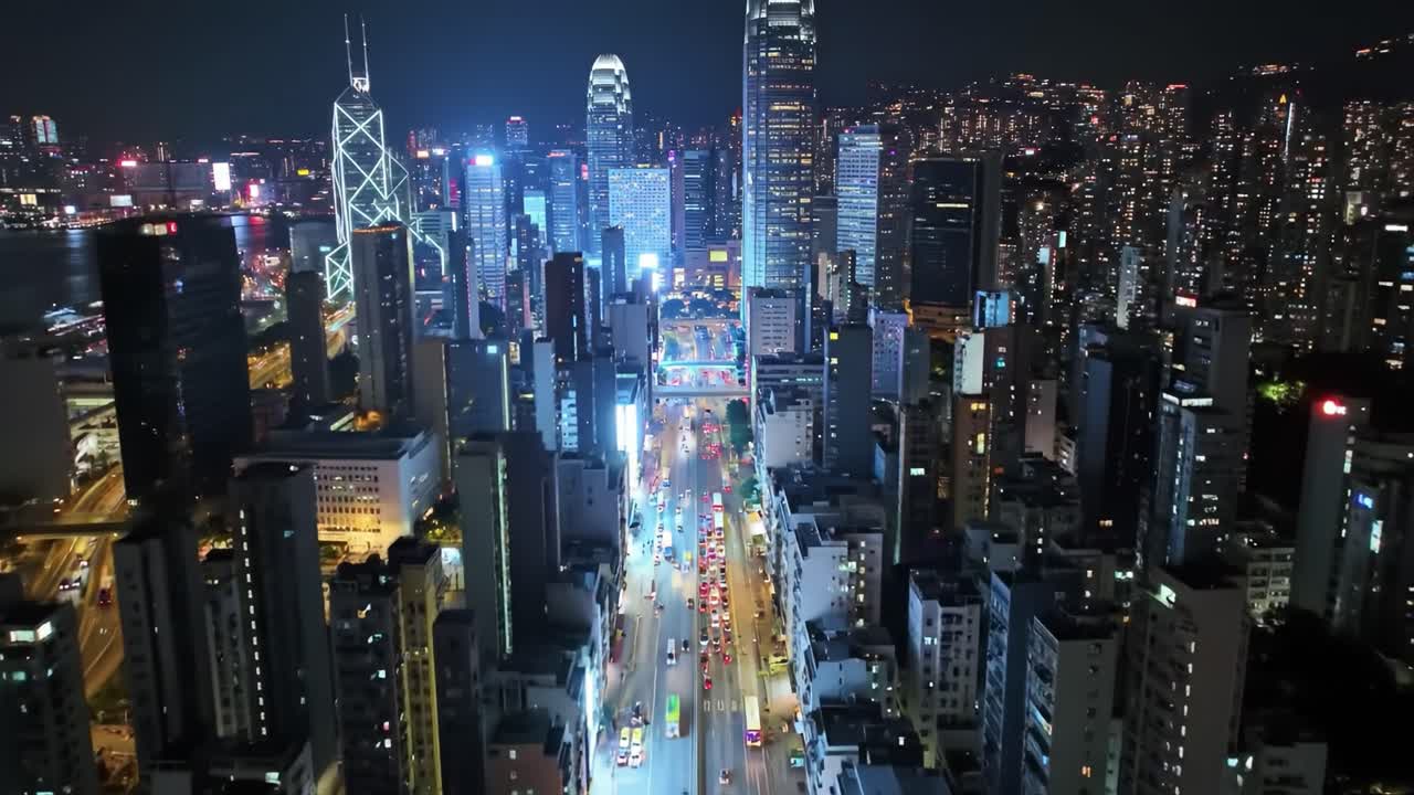 Experience the vibrant city life at night as bright lights reflect off towering skyscrapers and busy streets filled with cars. The skyline presents a stunning urban landscape.
