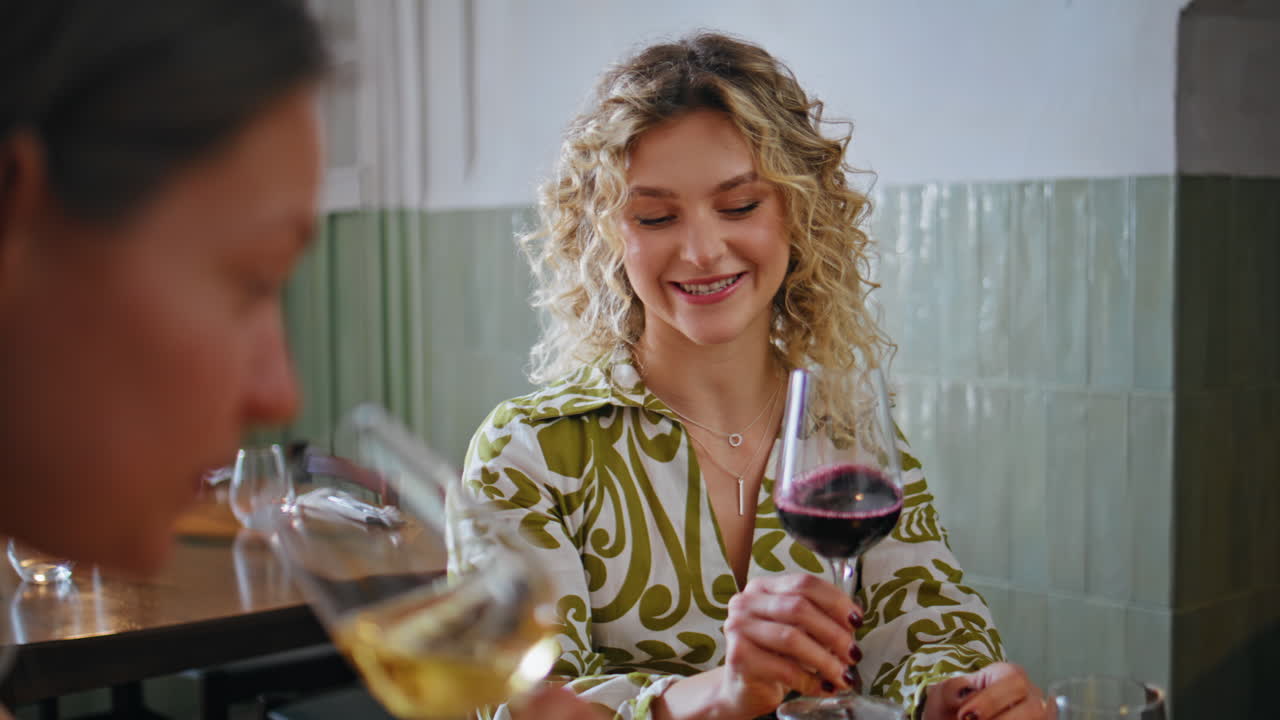 Primo piano di due amiche che bevono vino e chiacchierano in un ristorante