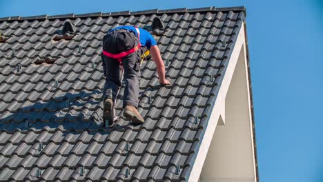 professional male roofer climbs down the roof