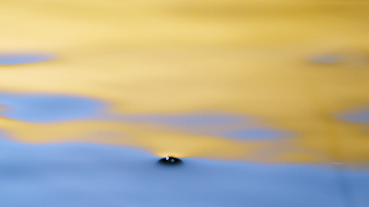 Close up real of water drop falls into water and diverging circles of water with smoot color background in studio with copy space for place a text for advertisement.
